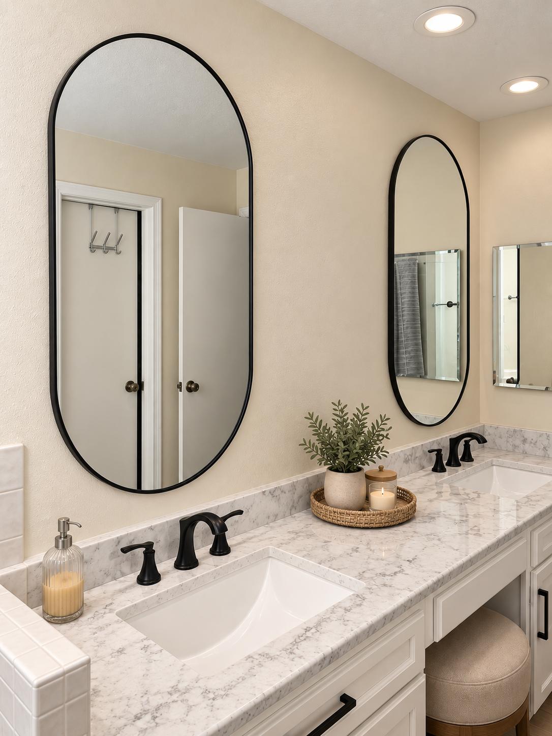Double vanity with marble-look countertop and oval black-framed mirrors