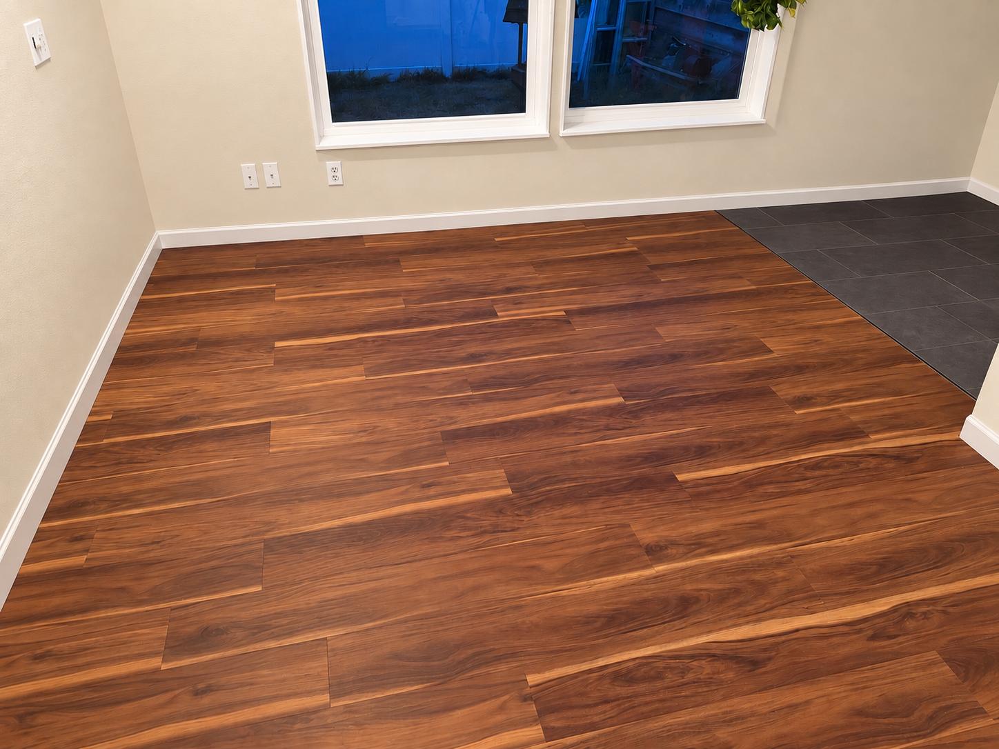 Wood-look plank flooring with new baseboards, tile, and a transition between the two